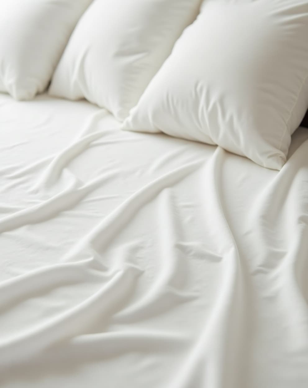 Close-up detail of crisp white bamboo bed sheets in soft morning light